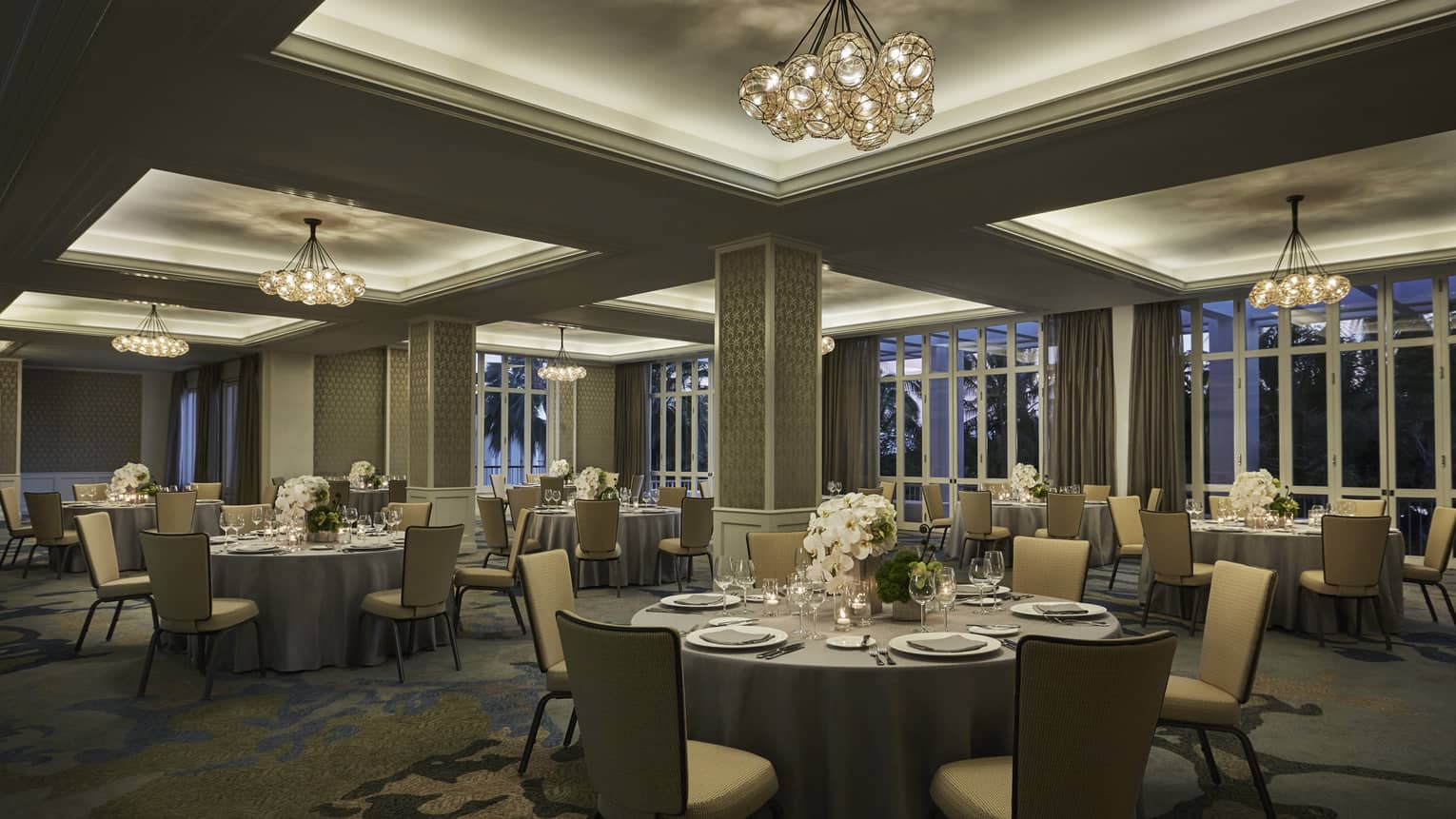 Round tables, chairs in dimly-lit Malolo Room banquet space 