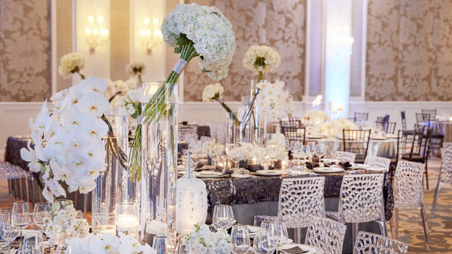 Elegant wedding reception tables set with white flowers, vases