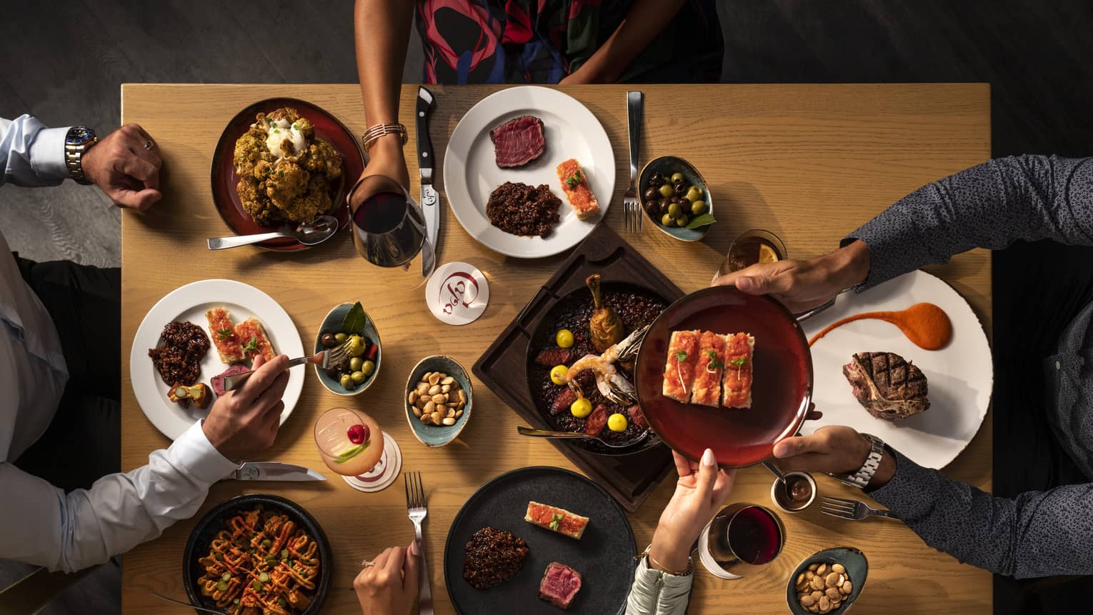 Aerial photo of people sitting around dining table passing plates of food.