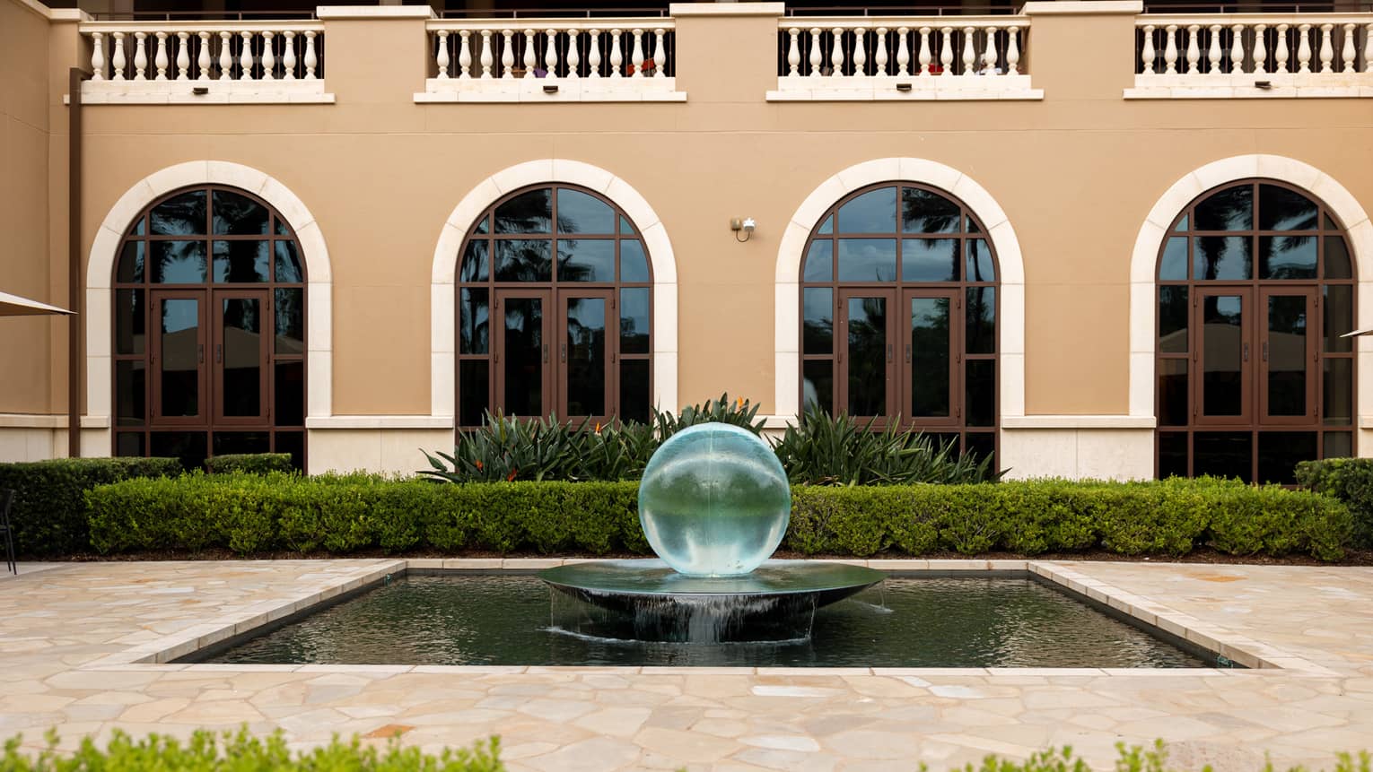 A water fountain in front of a building with arched windows