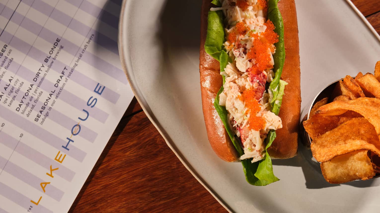 Lobster roll served next to potato chips on a white dish