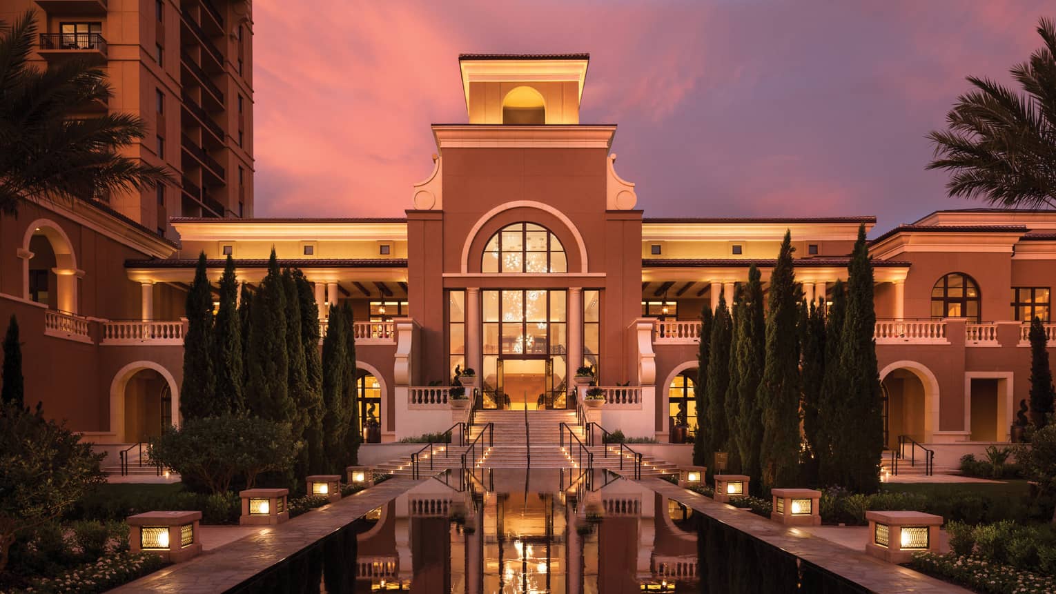 A fountain in front of a building at sunset