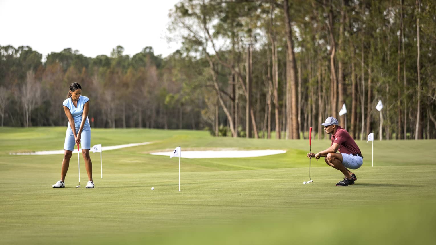 A woman playing golf makes a putt on the green 