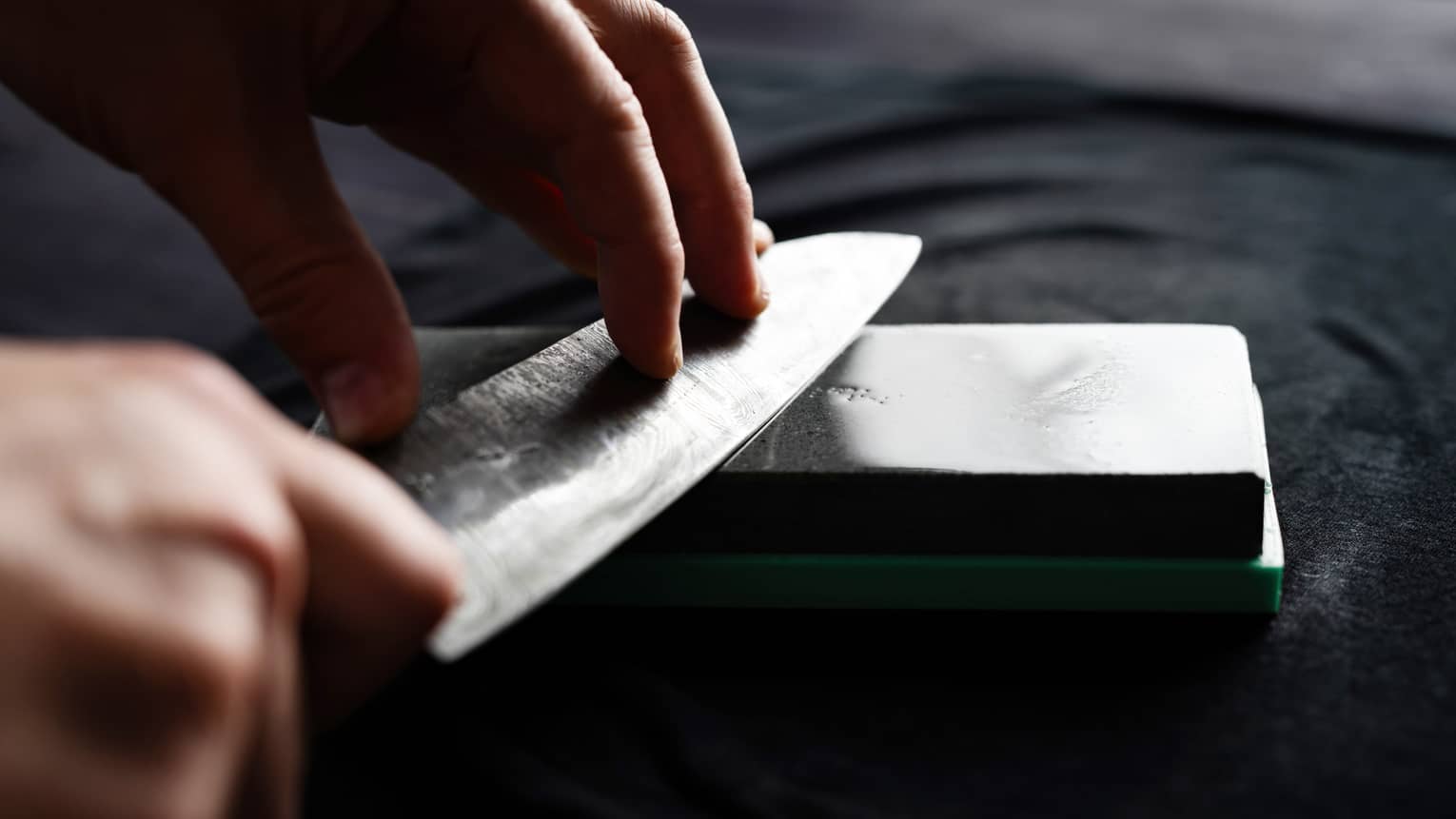 Hand sharpens knife on metal whetstone