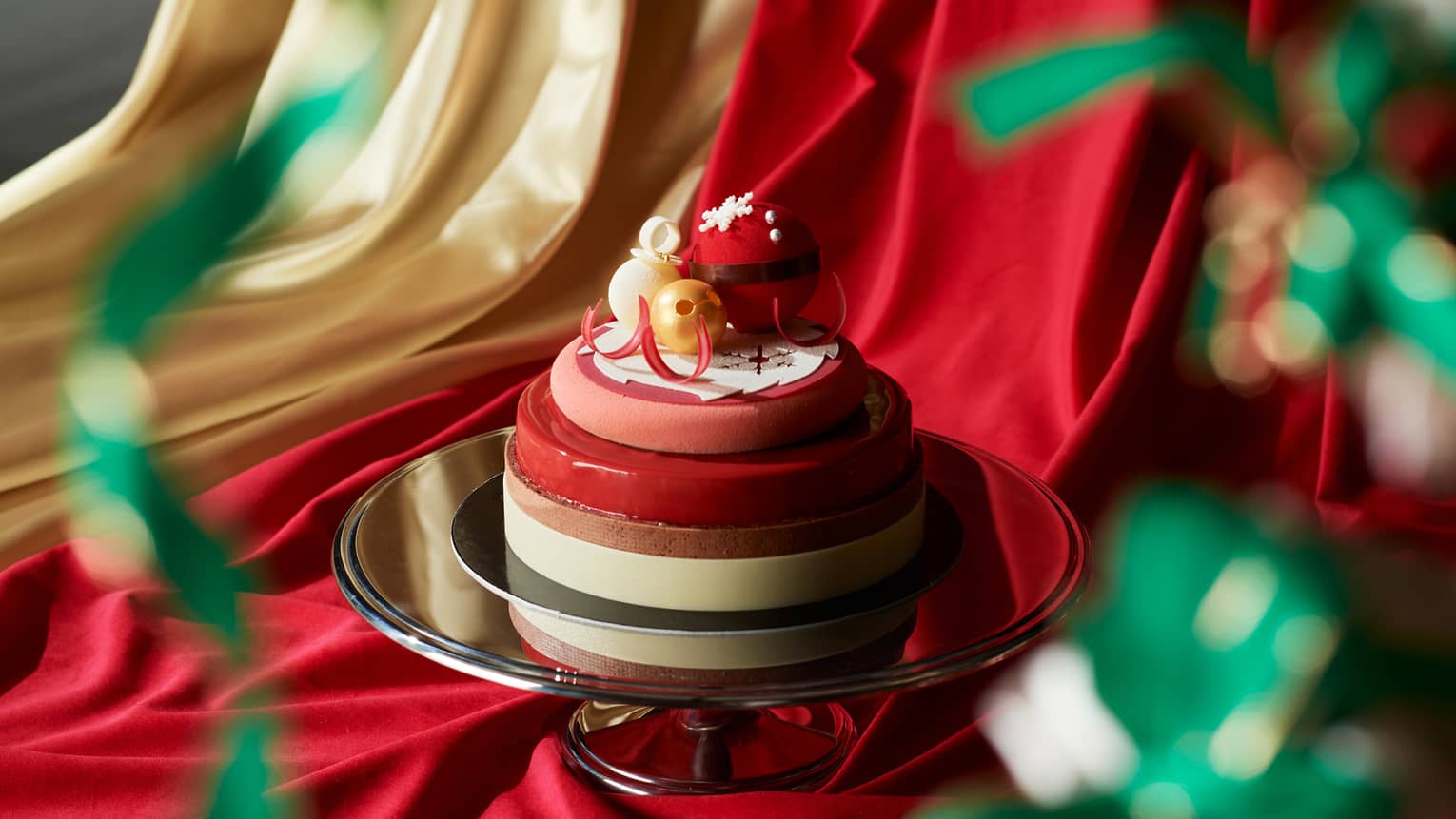 A red and beige cake on a silver tray.