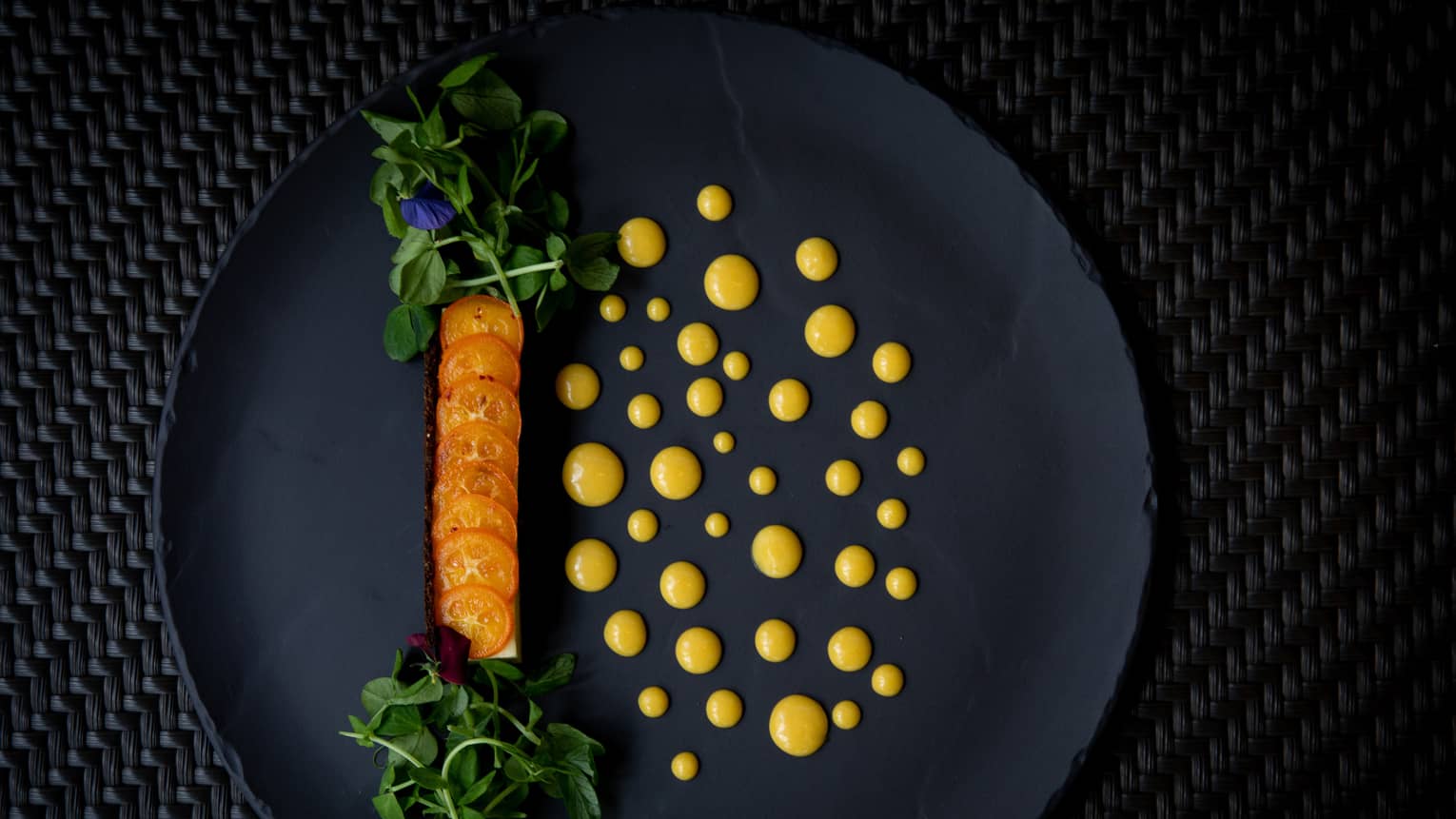 Slices of tomatoes with greens and dressing on a plate.