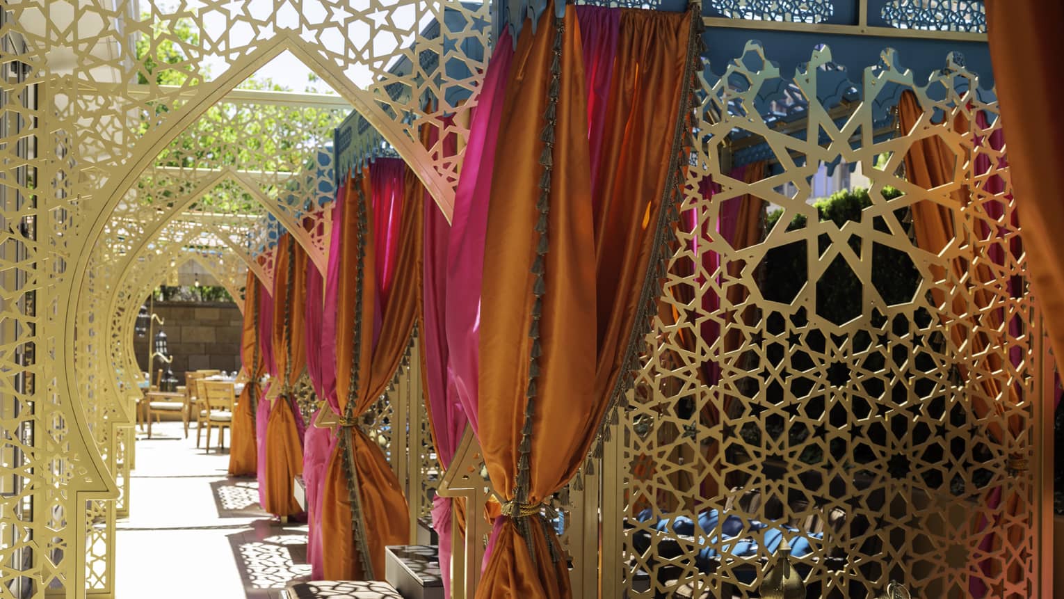 Patio decorated with gold Arabesque-style archways and curtains in pink, orange and blue