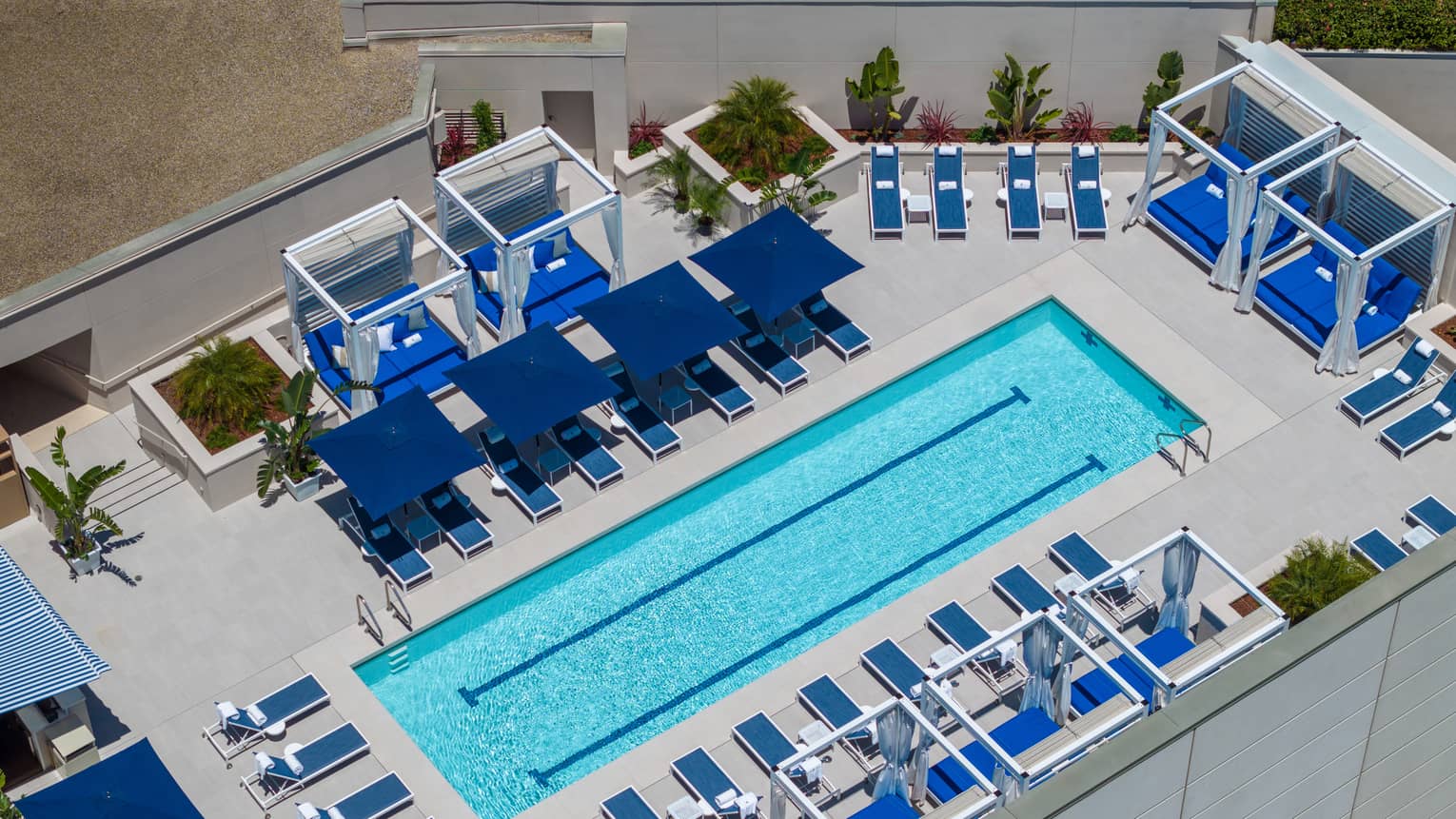 Aerial view of the pool with blue umbrellas and cabanas.