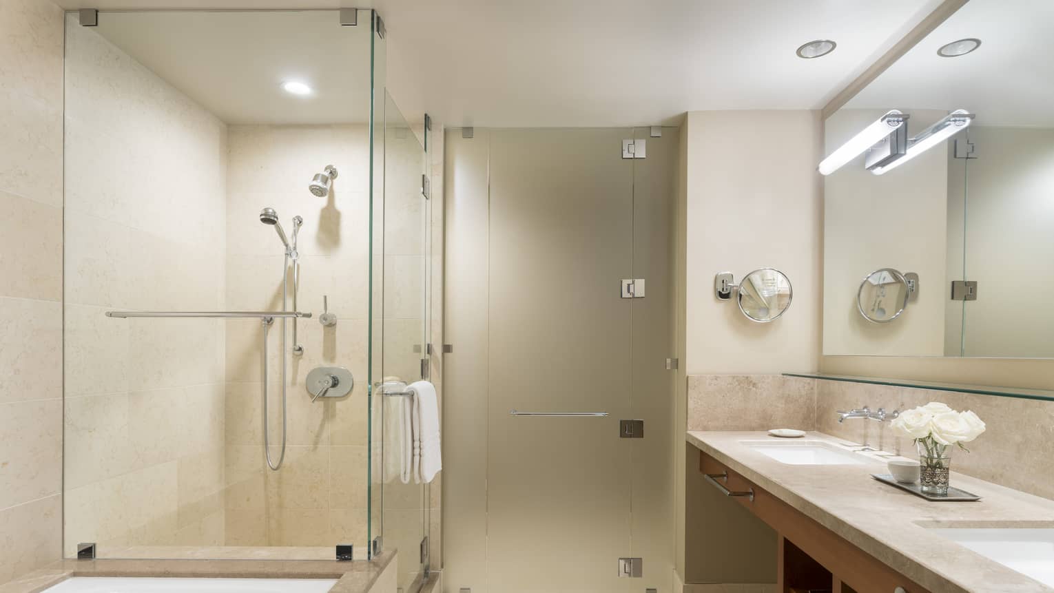 Bathroom with glass shower, bathtub and two sinks.