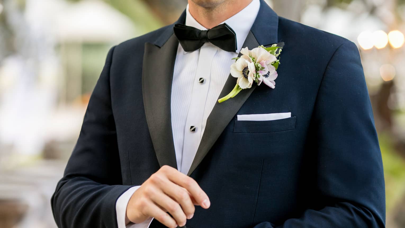 Groom wearing black and white tuxedo with white flower pinned to lapel