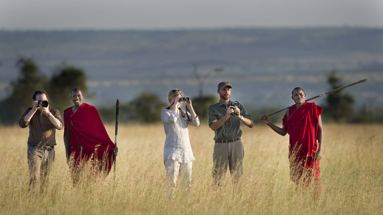 Couple takes photos on walking safari through tall grass with guides