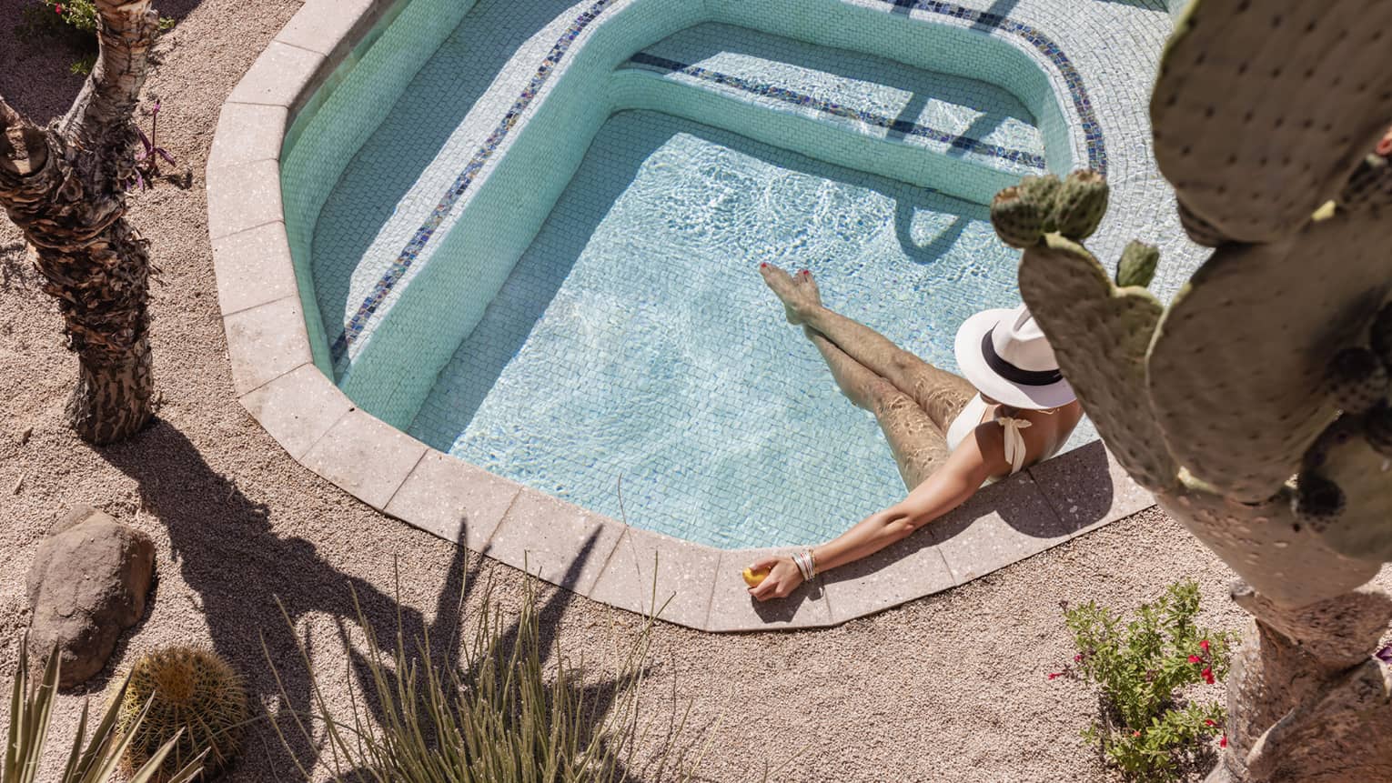 A woman in a plunge pool in a dessert.