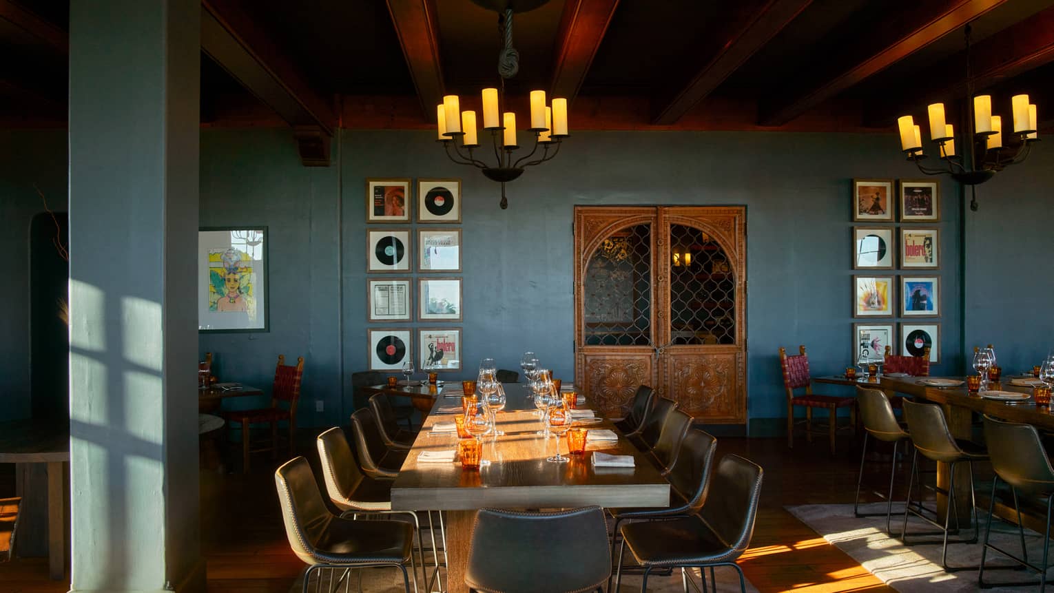 Dining room with blue walls and two chandeliers with candle lights.