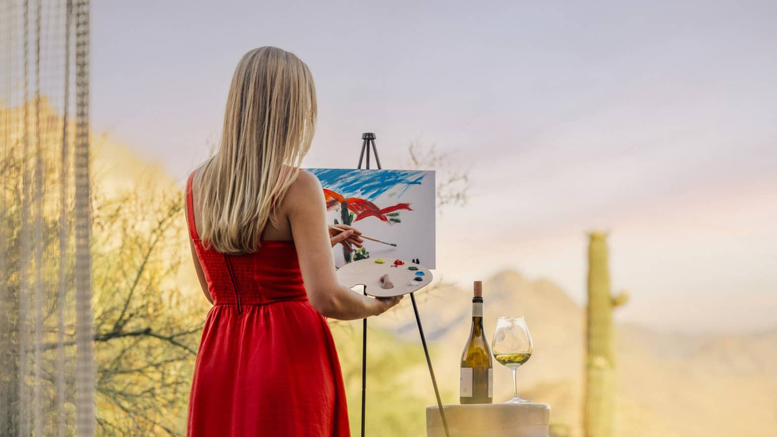 Person wearing a red dress and painting with a wine glass beside them.