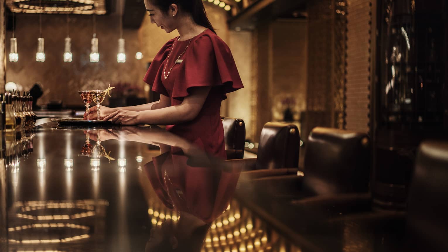 Woman wearing red dress at bar near tray with two cocktails in Charles H lounge
