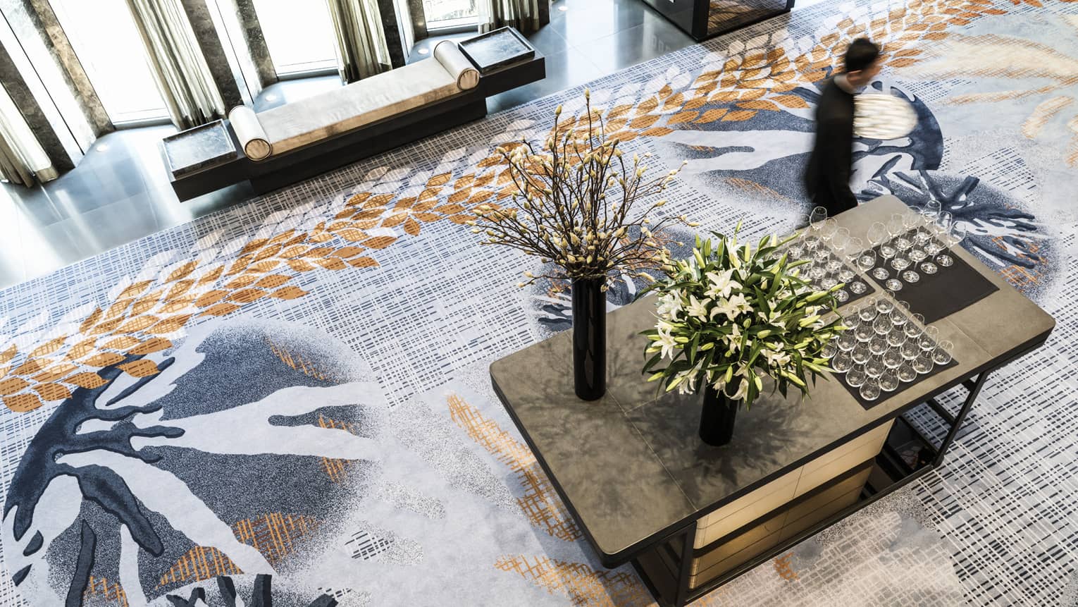 Aerial view of man walking past table with wine glasses and flowers in Nuri Ballroom Foyer