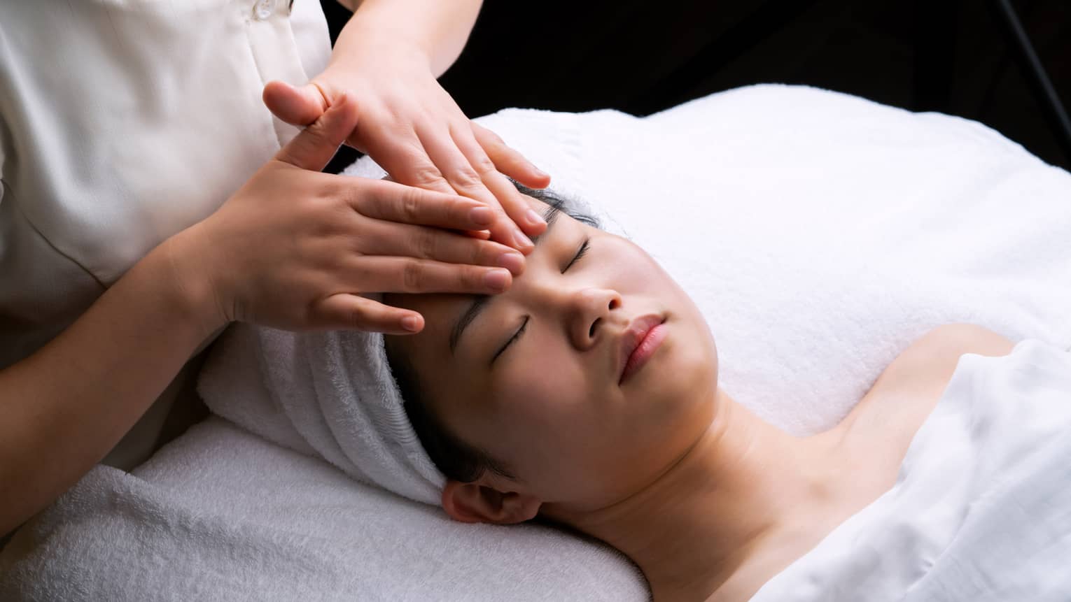 Spa staff places hands on woman's forehead during Anti-Oxidant Facial