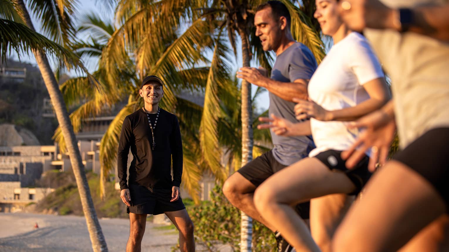 Fitness instructor leading an outdoor workout class with three guests.