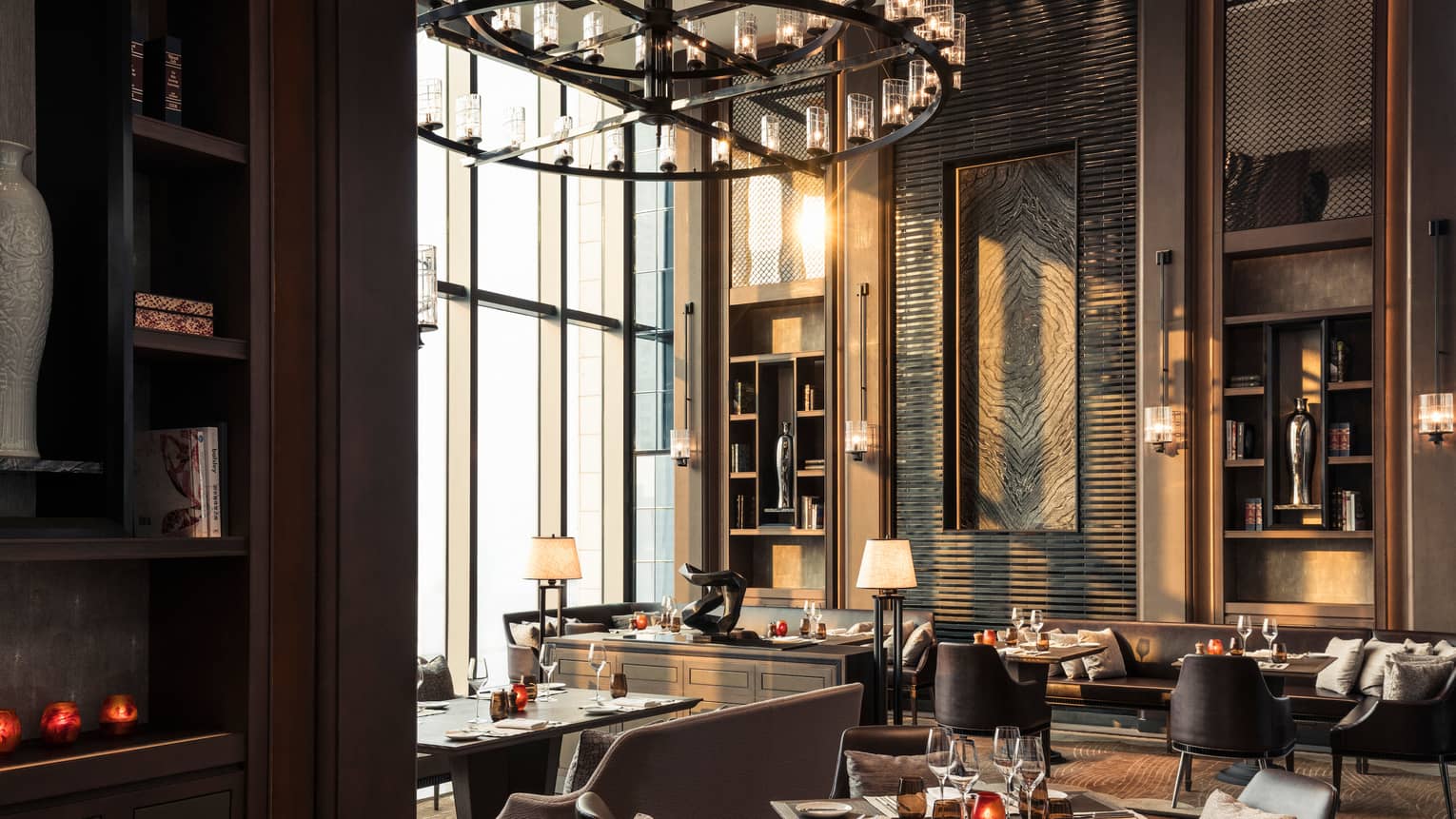 Cielo dining room, tables and chairs under sunny window, large round chandelier with candles