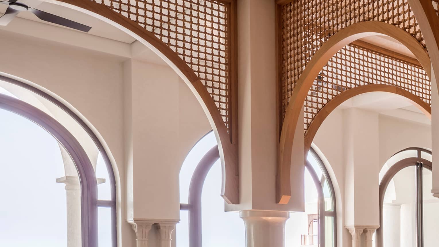 Restaurant dining area with archways, set square tables, tan leather dining chairs, water view