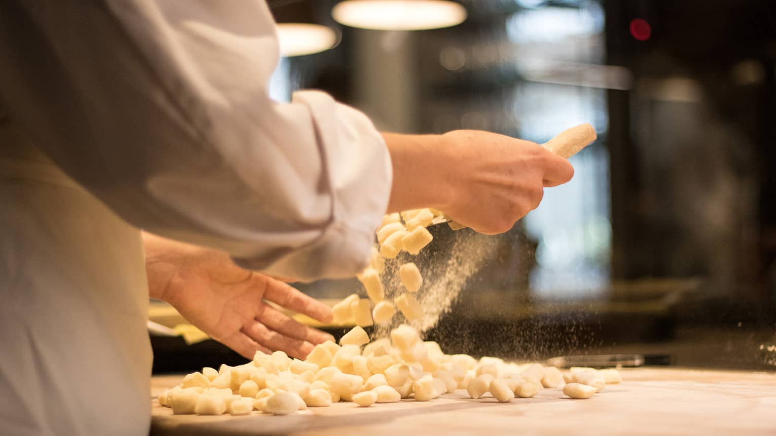 Chef making pasta noodles on a table.