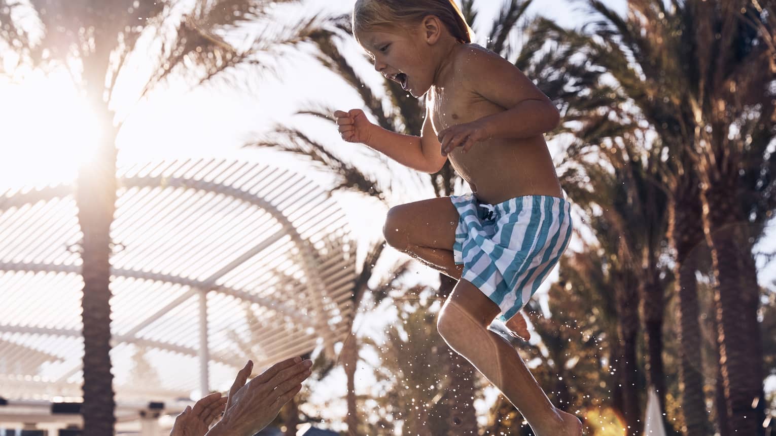 Child laughing while being thrown into air in the pool.