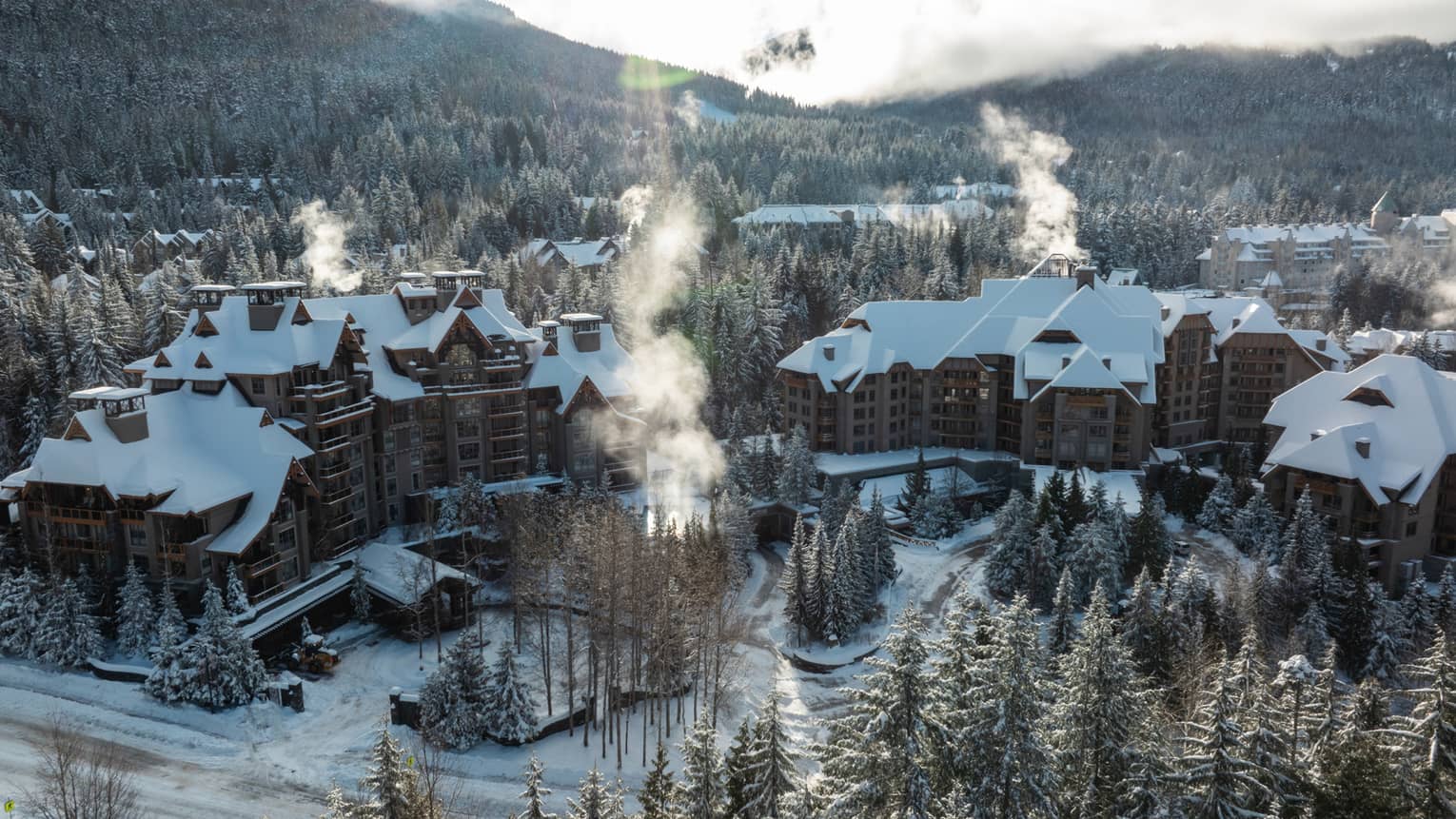 Exterior of property in winter with snow-topped roof and mountains in background
