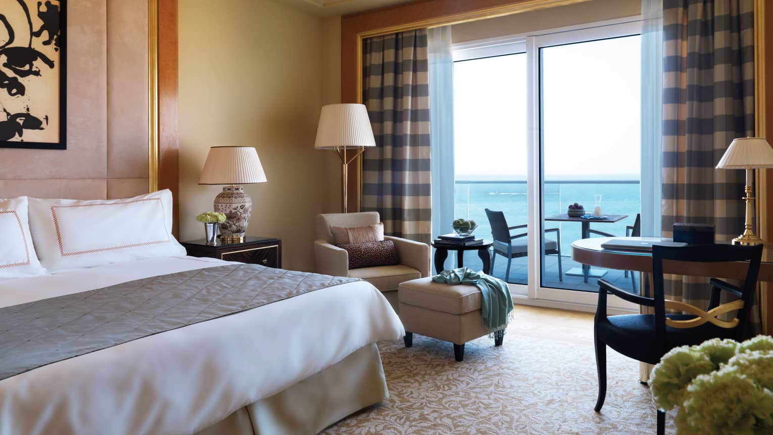 Premium Room with king size bed, armchair and plush ottoman beside patio door with blue checkered curtains