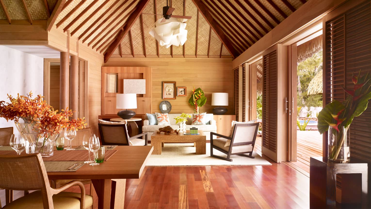 Two-bedroom beachfront villa living room with white sofa and chairs, cathedral ceilings, hardwood floors