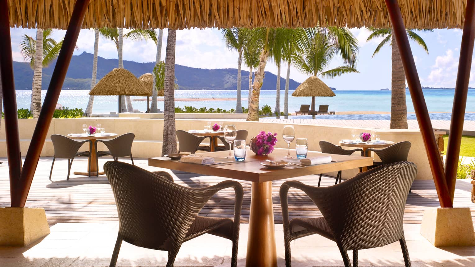 Tere Nui dining table with wicker chair looking out at sunny patio, ocean