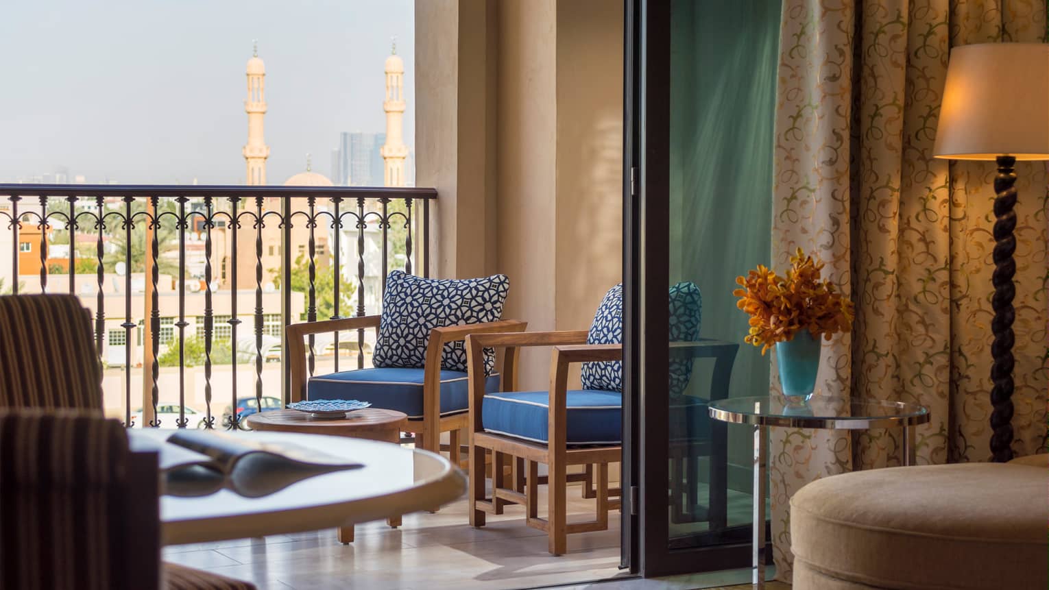 Deluxe City View room looking out at patio with two wood chairs and blue cushions, Dubai skyline views