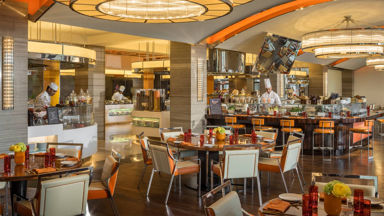 Suq market-style casual dining room with white-and-orange decor, chefs at cafeteria-style counters