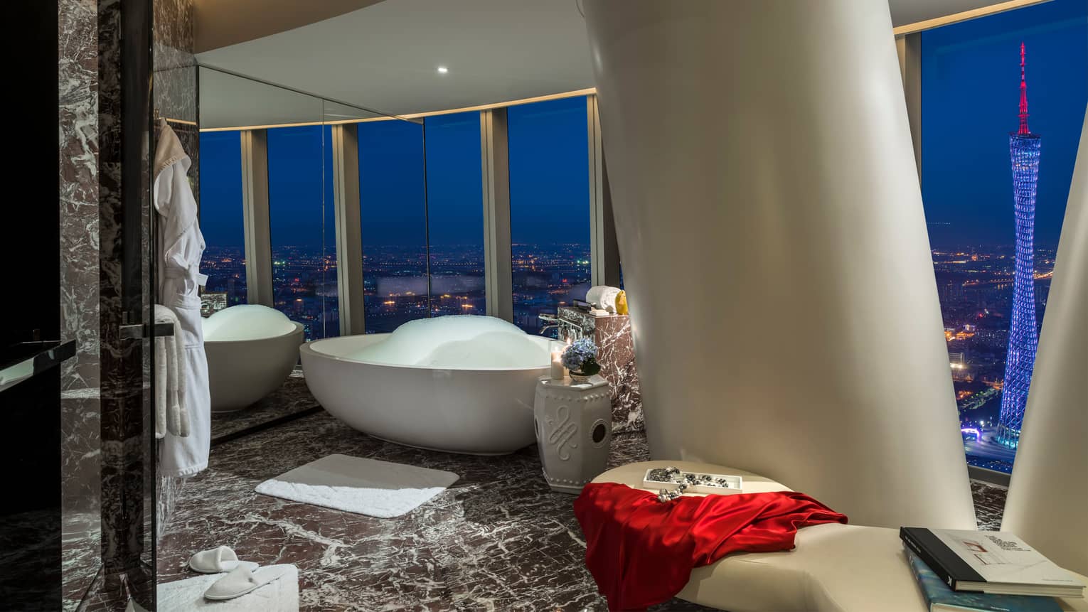 Free-standing white tub beside white column in marble bathroom, panoramic night views with Canton Tower