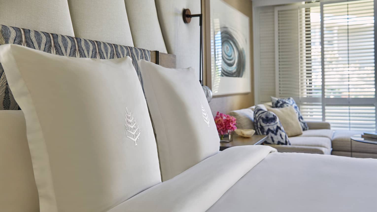 Garden-View suite pillows and bed linens with Four Seasons logo, white sofa and blue pillows in background