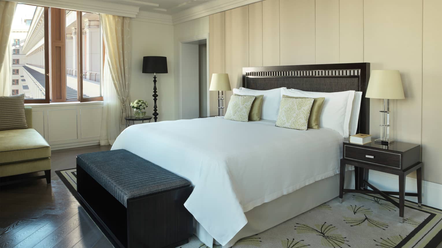 Premier Suite bed with gold accent pillows, grey bench, window with view of Four Seasons Hotel exterior