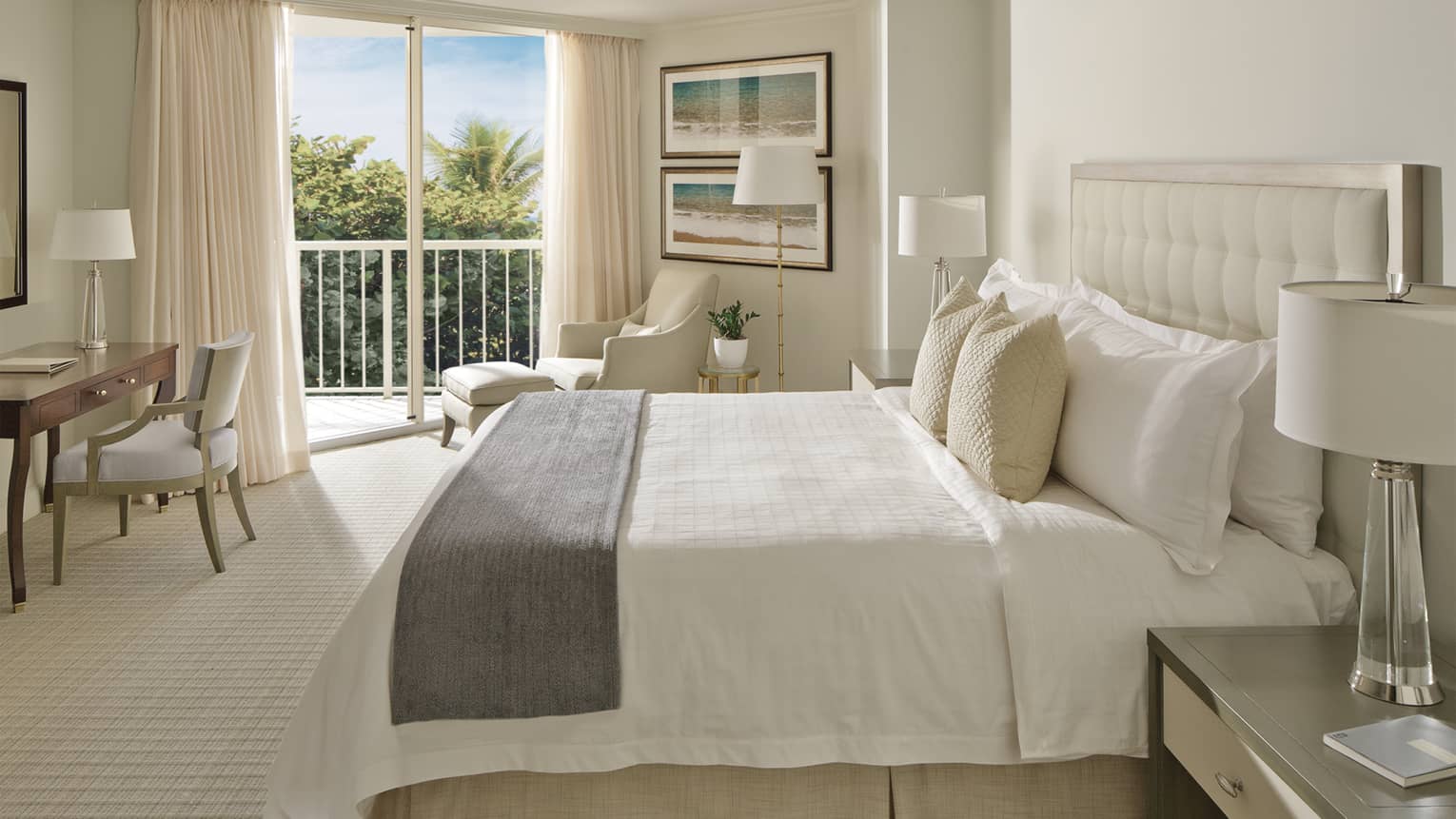 Garden-View Room bed with ivory pillows, grey bedspread, office desk and balcony