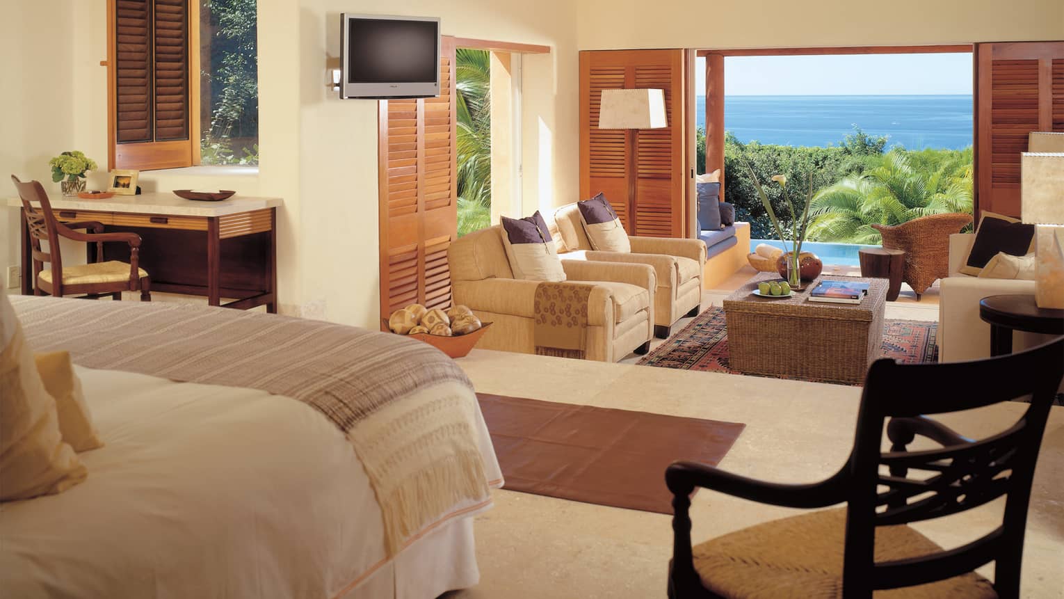 Private residence split-level room with bed, desk and TV looking down on living room, open door to patio