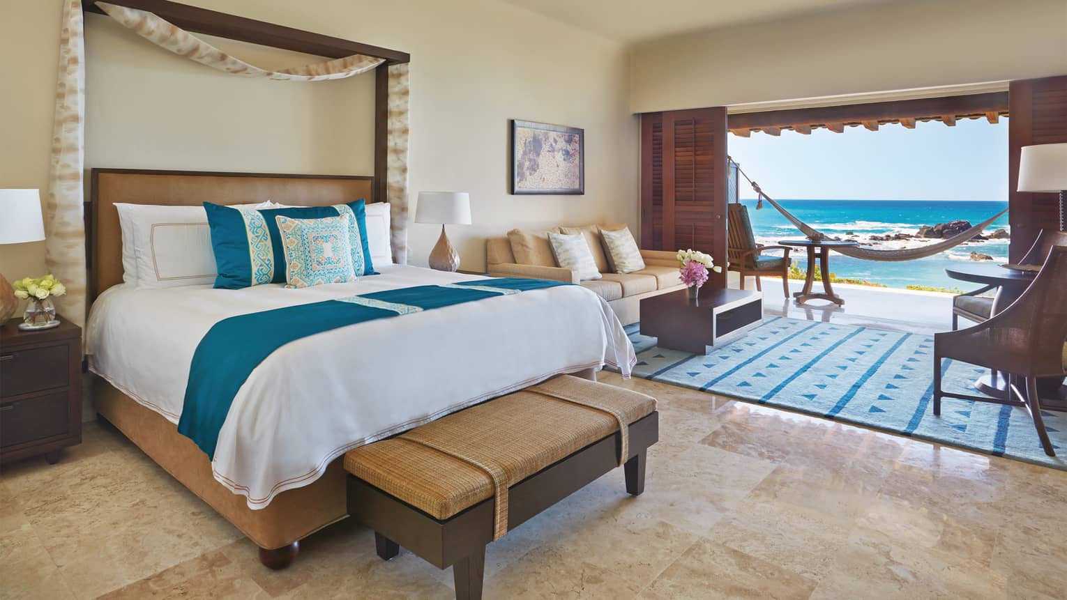 Casita oceanfront room with bed, blue-and-yellow print pillows, living room and patio, hammock overlooking ocean,