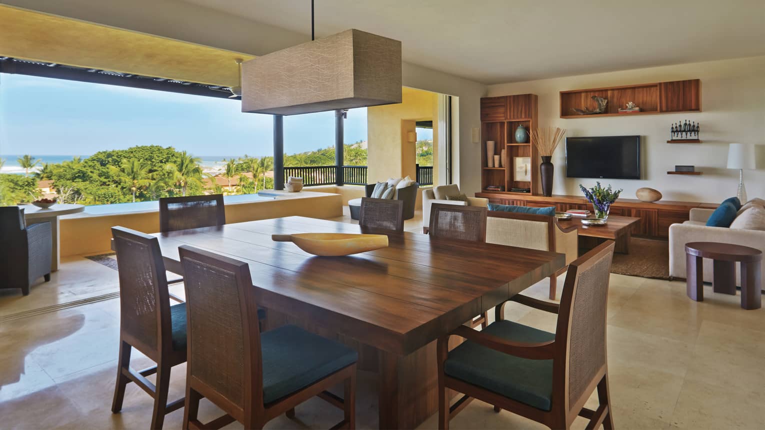 Private residence six-person dining table with dark wood and teal cushions, rectangular chandelier, living room