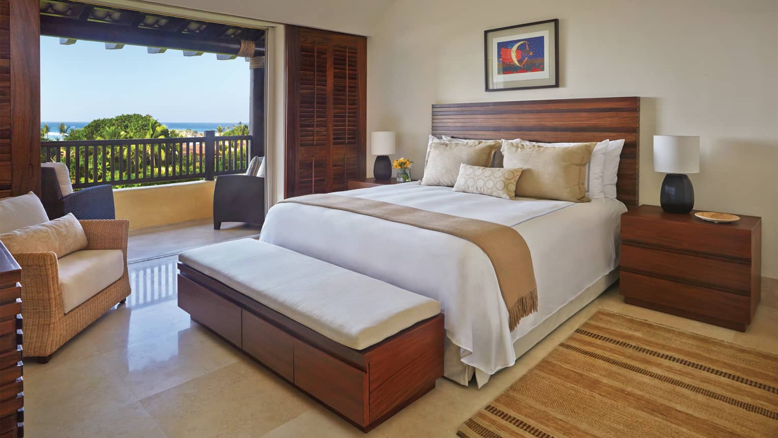 Private ocean view penthouse bedroom with tile floor, modern wood decor, wicker armchair and open patio door