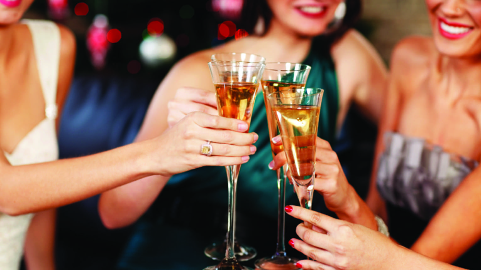 Close-up of women in evening gowns toasting with glasses of Champagne