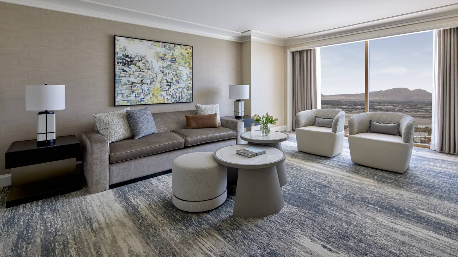 Sitting area with two chairs, large window, coffee table and sofa.