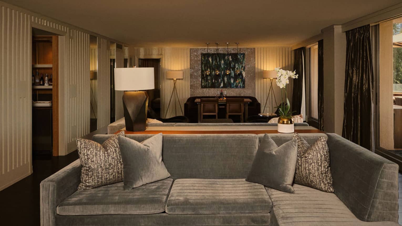 Contemporary hotel suite featuring a grey sofa and walk-out terrace