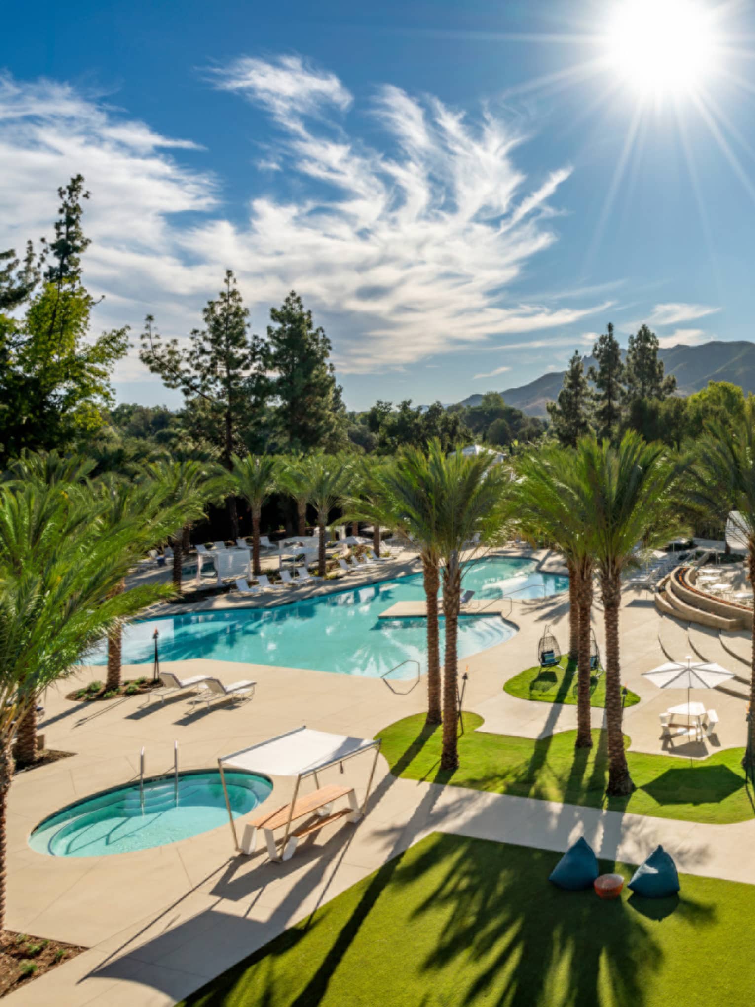 Aerial view of the pool with sunlight and palm trees.