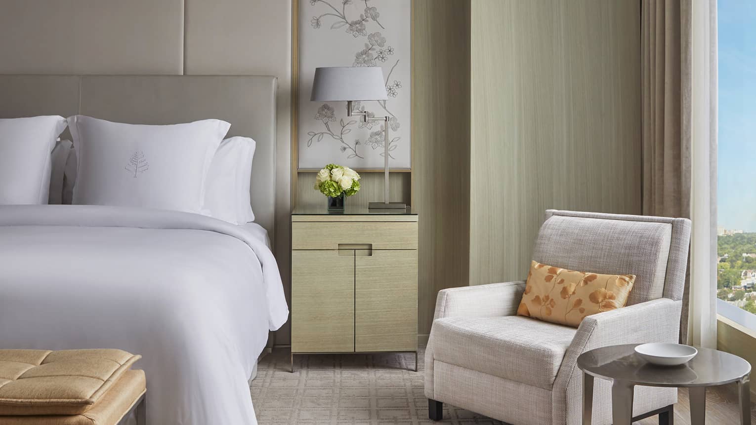 Bed with side table and lamp, arm chair next to window