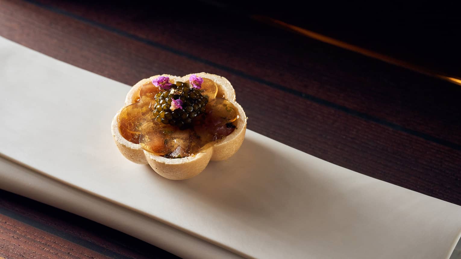 Meal prepared in shape of a flower with purple flowers on top.