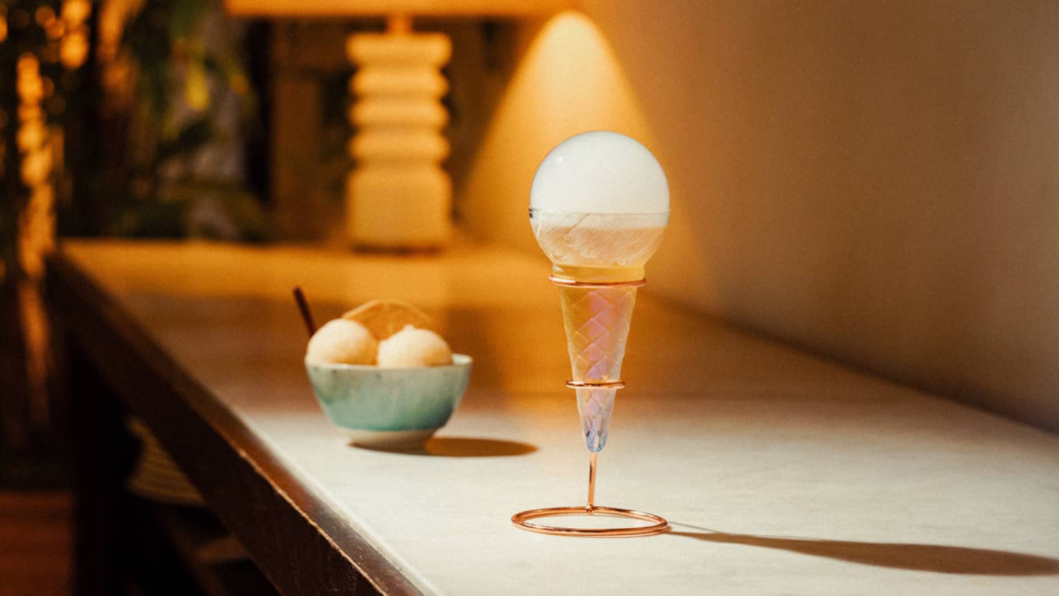 Azucar presented in a cone-shaped holder with a bowl of sorbet in the background