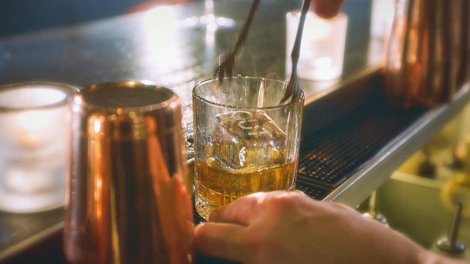 Bartender's hands making an Old Fashioned on a bar counter