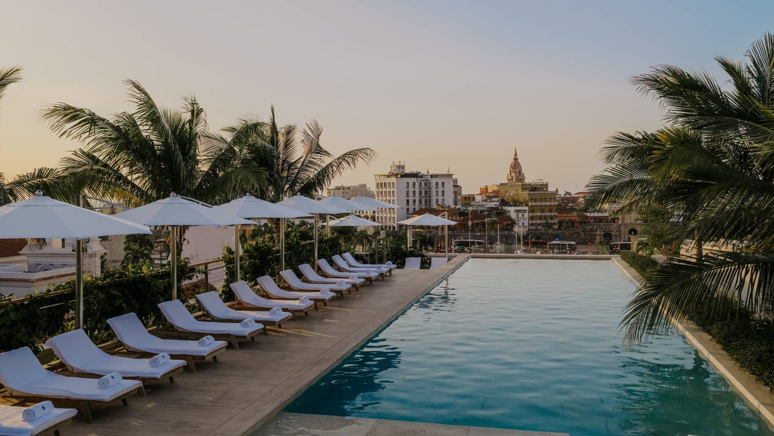 White lounge chairs and umbrellas line the outdoor pool