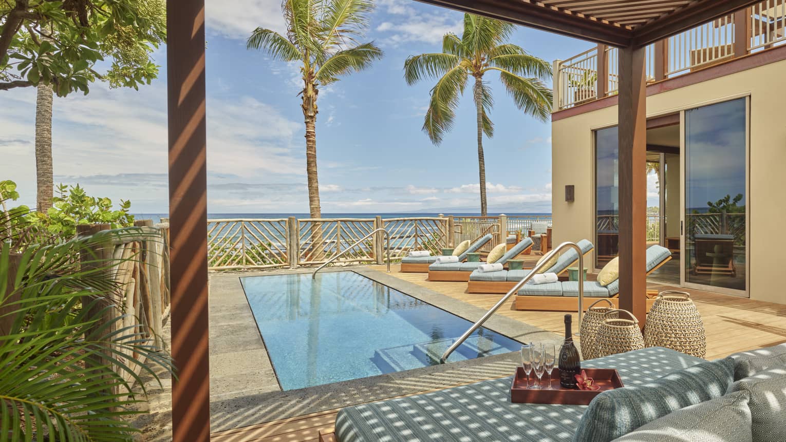 Rectangular outdoor pool on private terrace, four lounge chairs, beach view